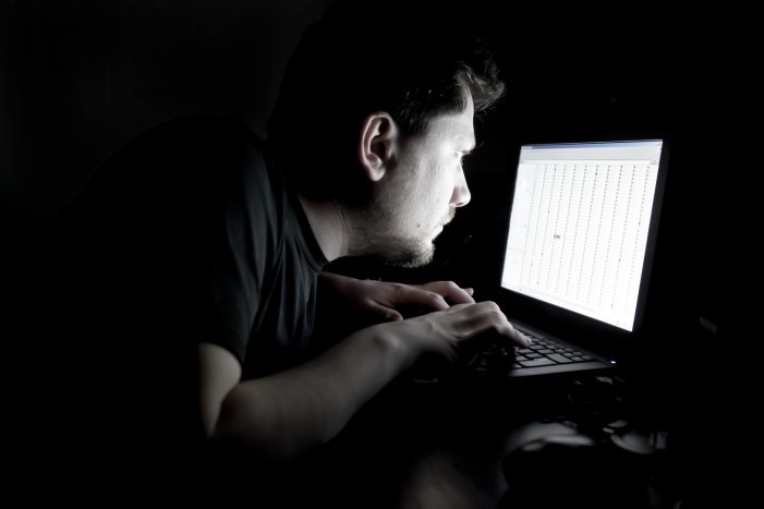Man working on laptop in the dark